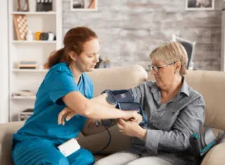Nurse taking blood pressure of a patient on a sofa.
