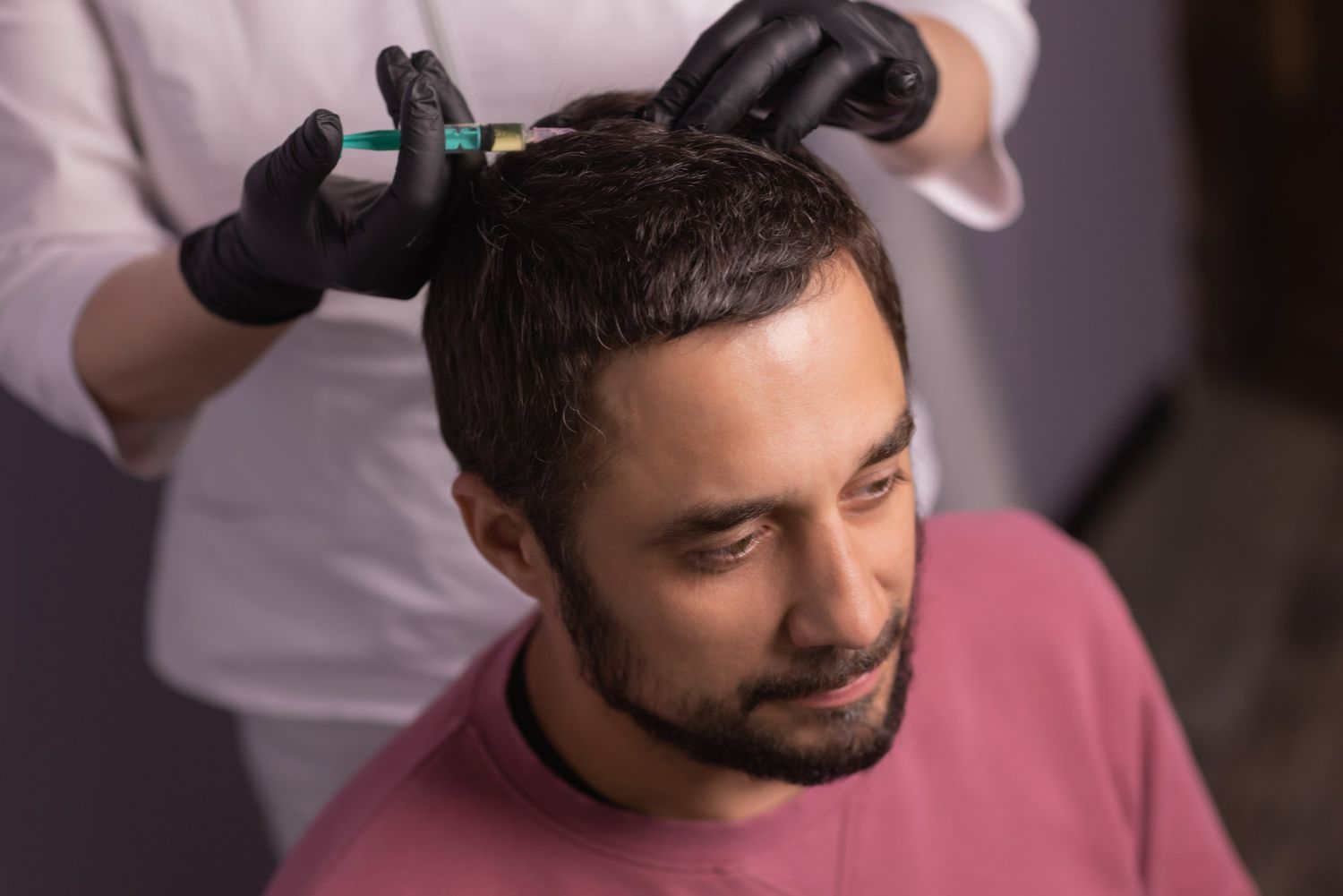 Hairdresser applying product to a man's short dark hair in a salon