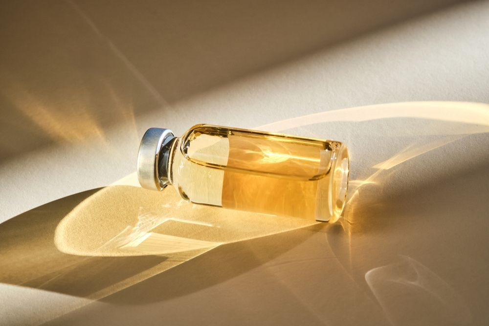Clear bottle of golden liquid lying on its side in warm sunlight, casting soft shadows