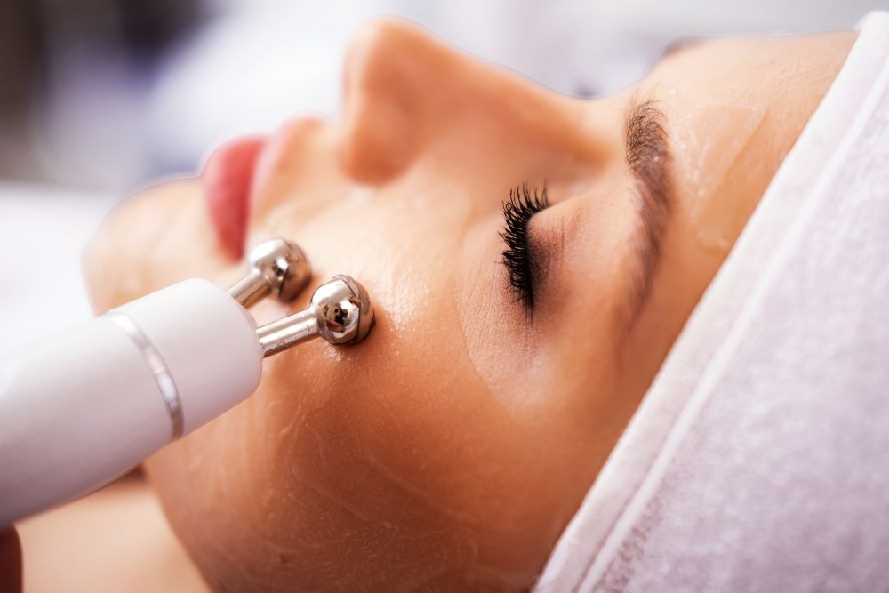 Facial treatment device on a person’s face, with metal rollers near the eye and cheek