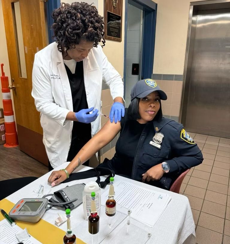 A police officer is getting a vaccine from a doctor