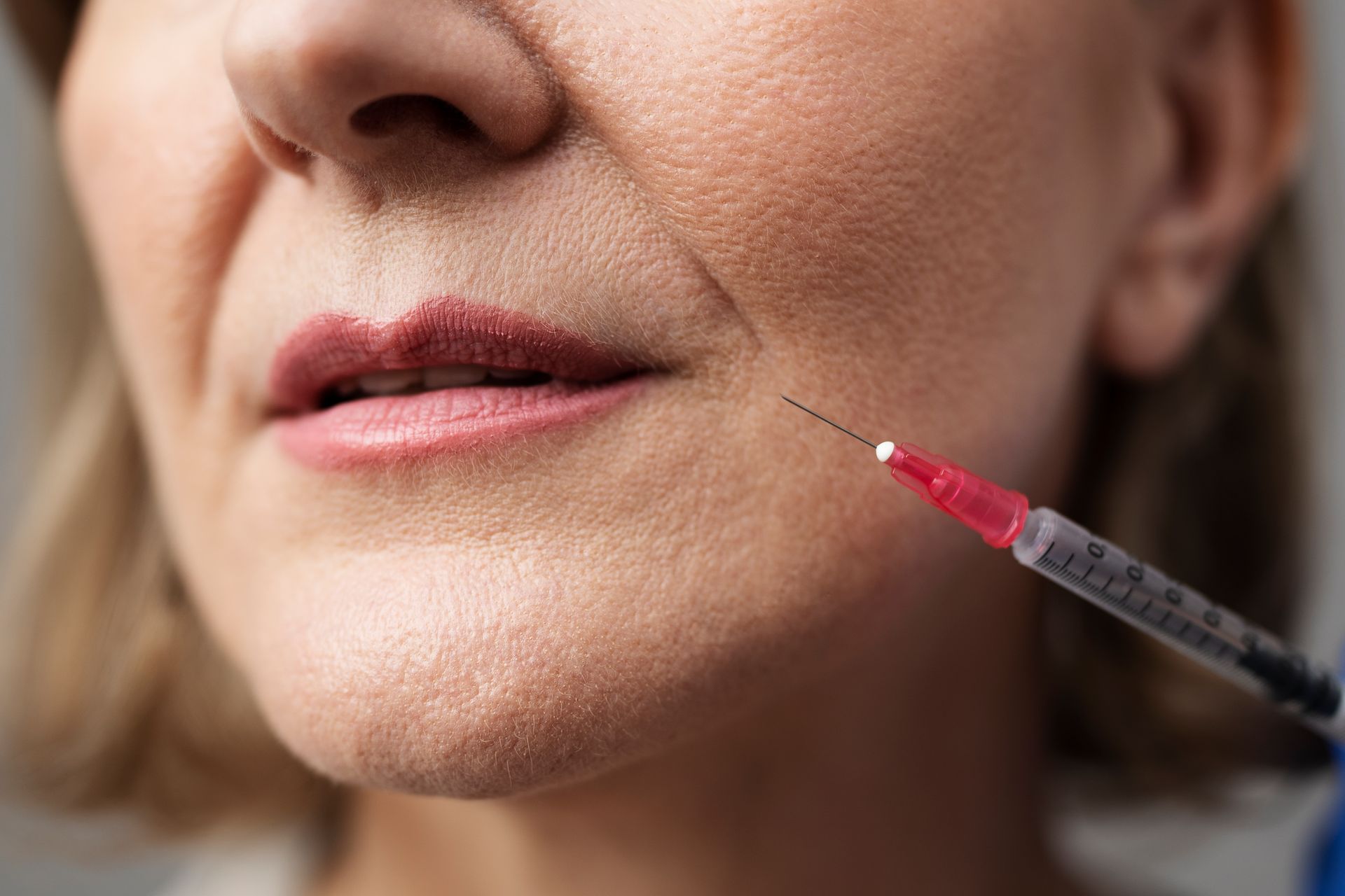 Syringe injecting the side of a person's mouth.