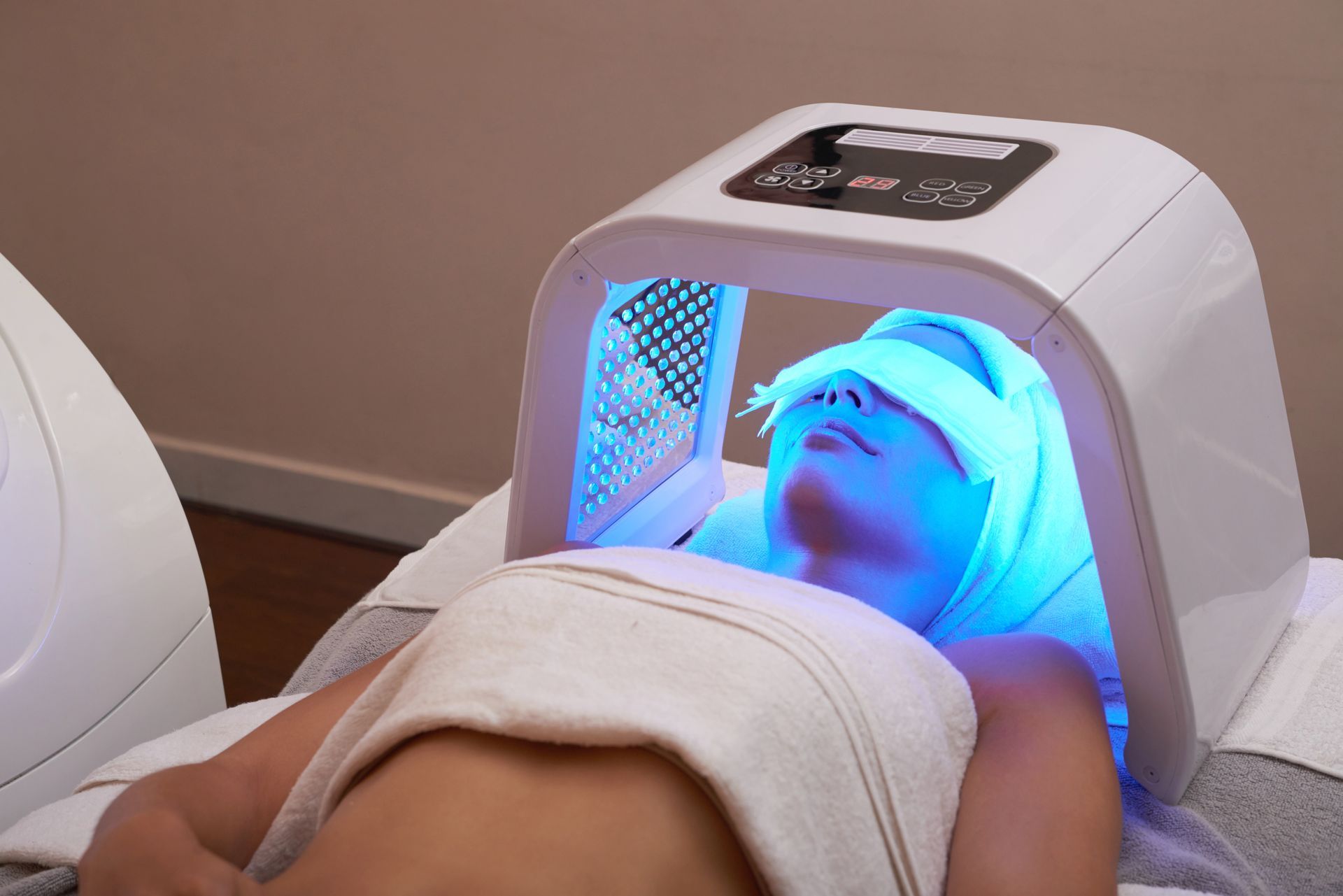 A woman is getting a treatment with a blue light on her face