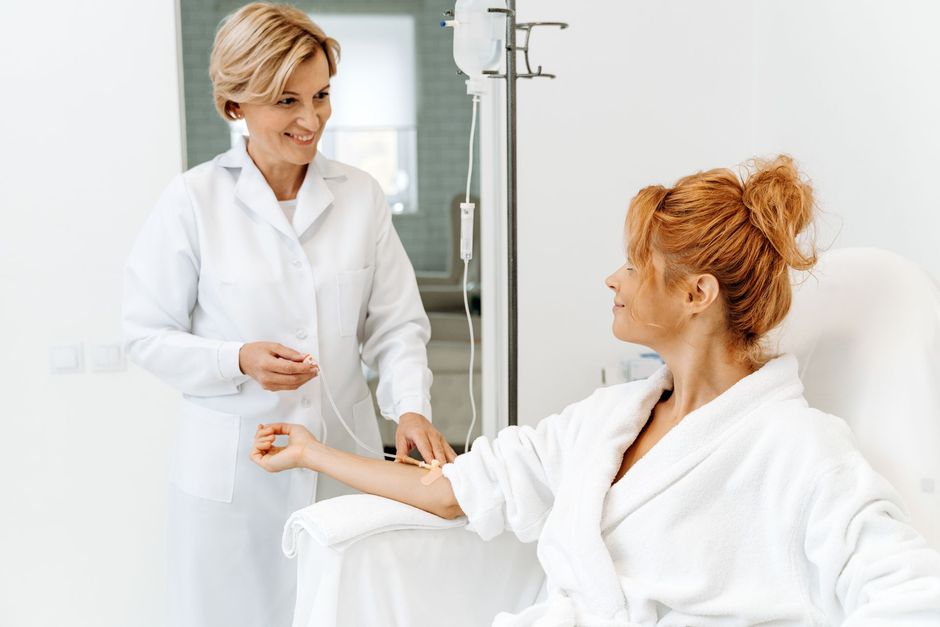 A doctor is giving an iv to a patient in a hospital bed.