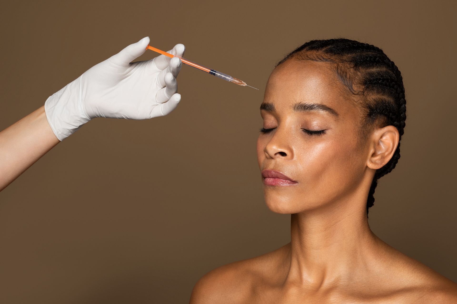 A woman is getting a botox injection in her forehead.