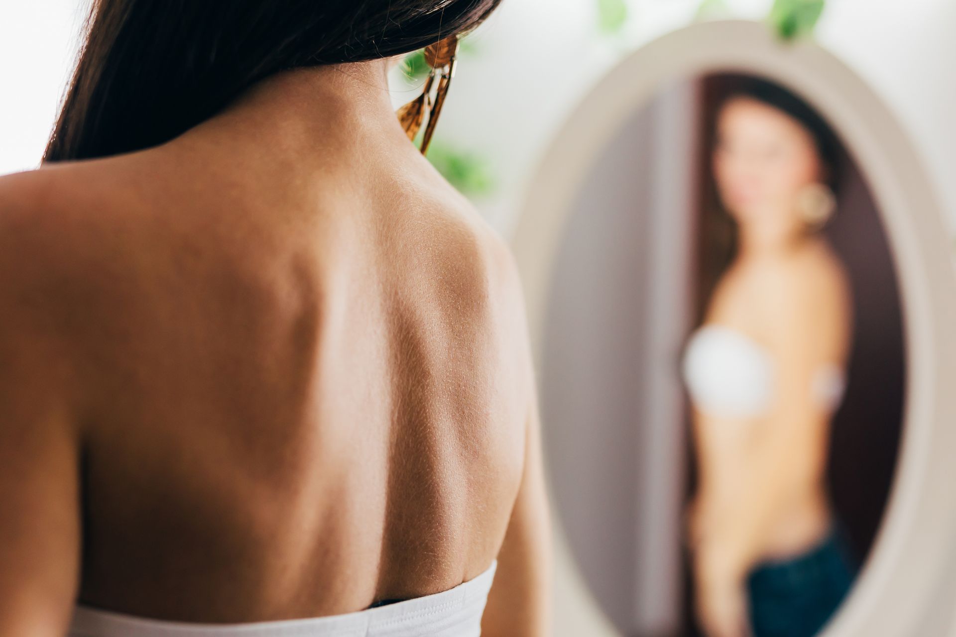 A woman is looking at her reflection in a mirror.