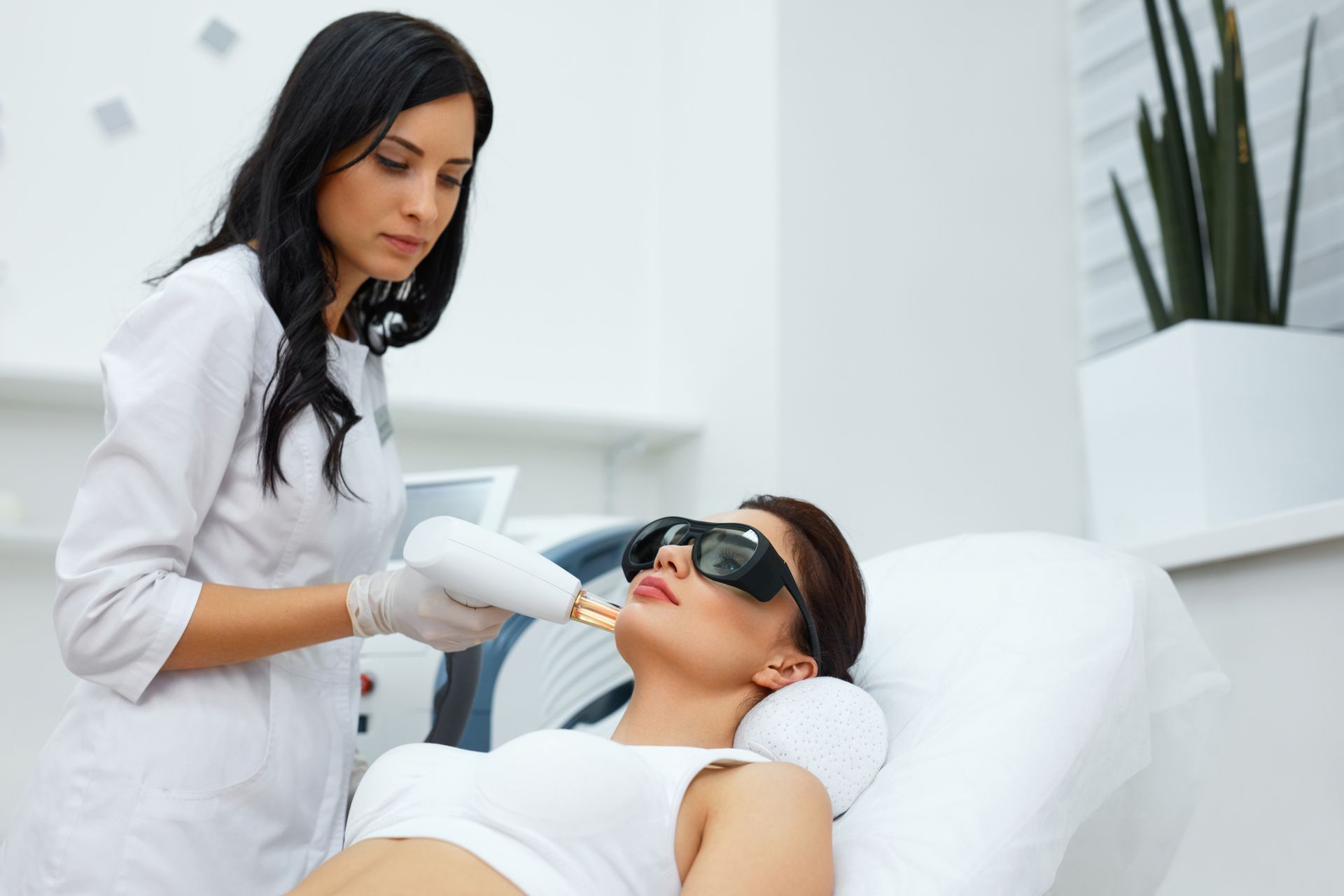 A woman is getting a laser hair removal treatment on her face.