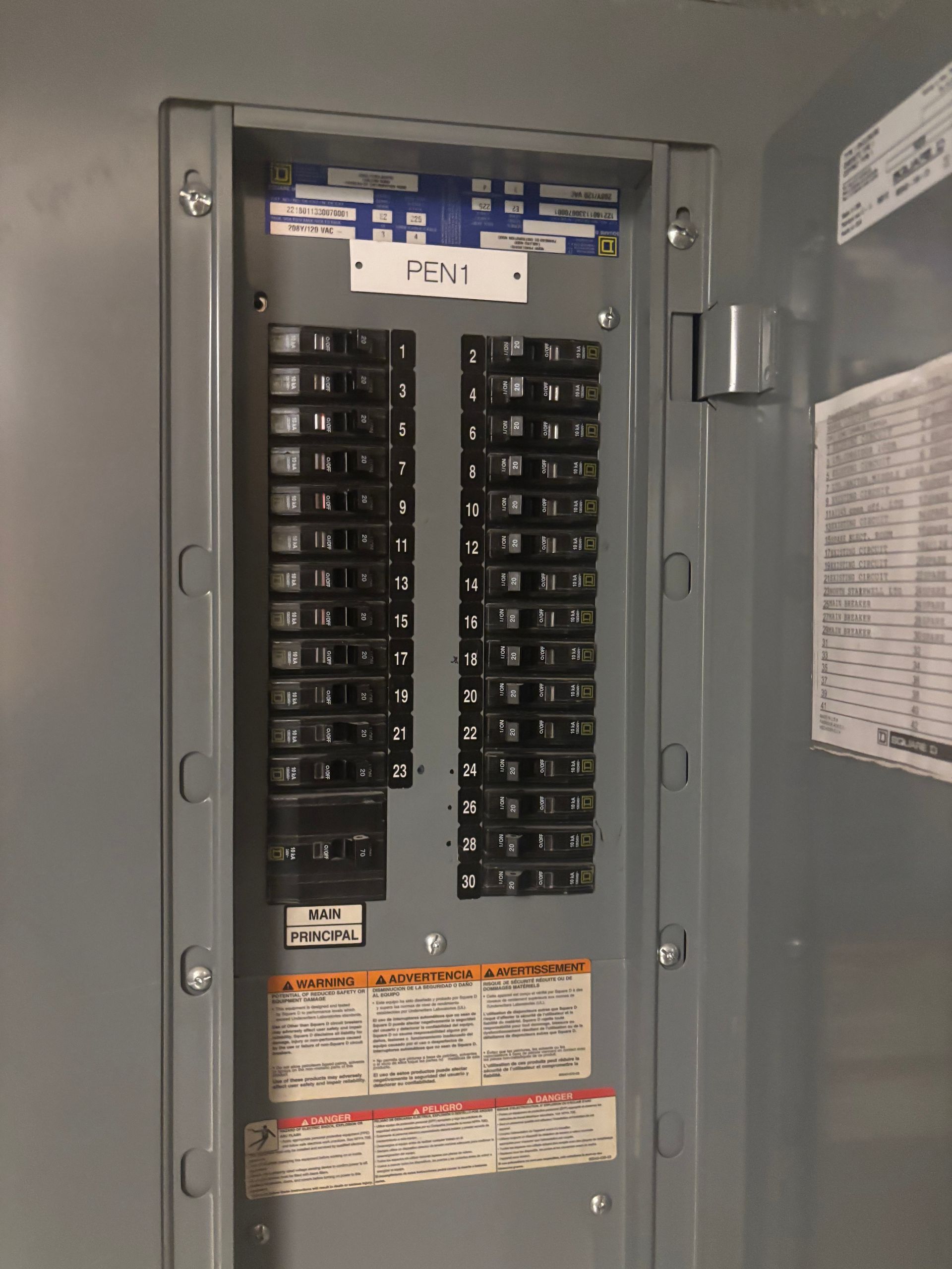 Construction site interior with exposed wiring, ductwork, and concrete ceiling near windows.