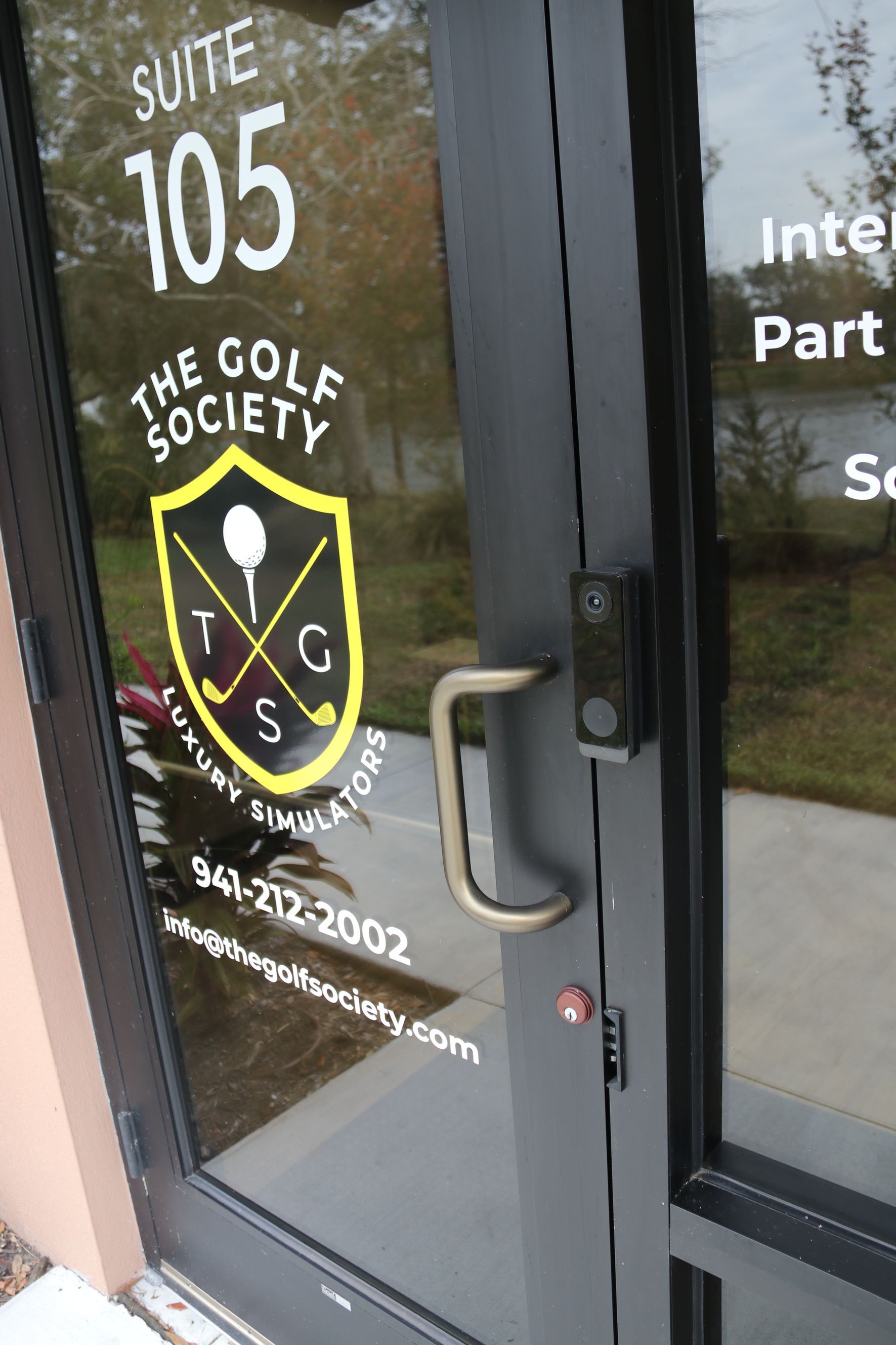 Glass door to Suite 105 for The Golf Society, with logo and handle.