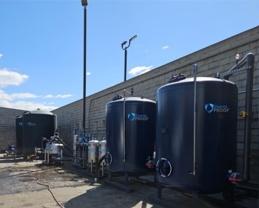 Blue industrial tanks and piping outside a building under a clear sky.