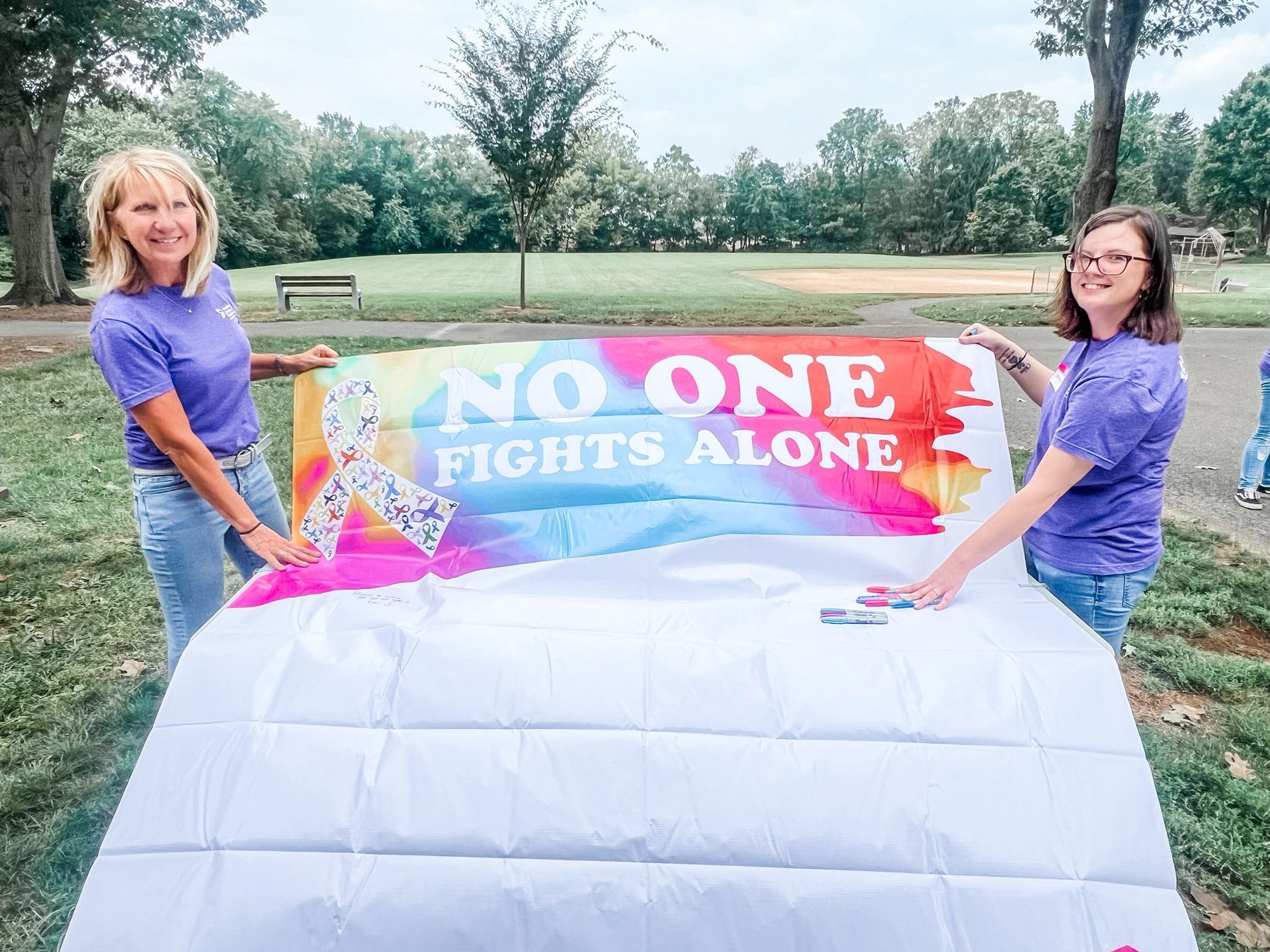Two people hold a colorful banner with