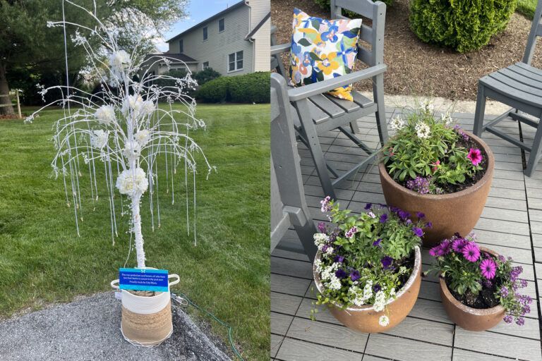 White decorative tree with hanging strands and flower planters on a patio with furniture and a house in the background.