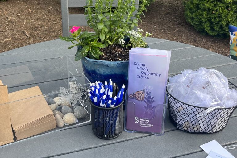 Table with craft supplies: pencils, bags, brochure, flower pot, rocks, and a basket.
