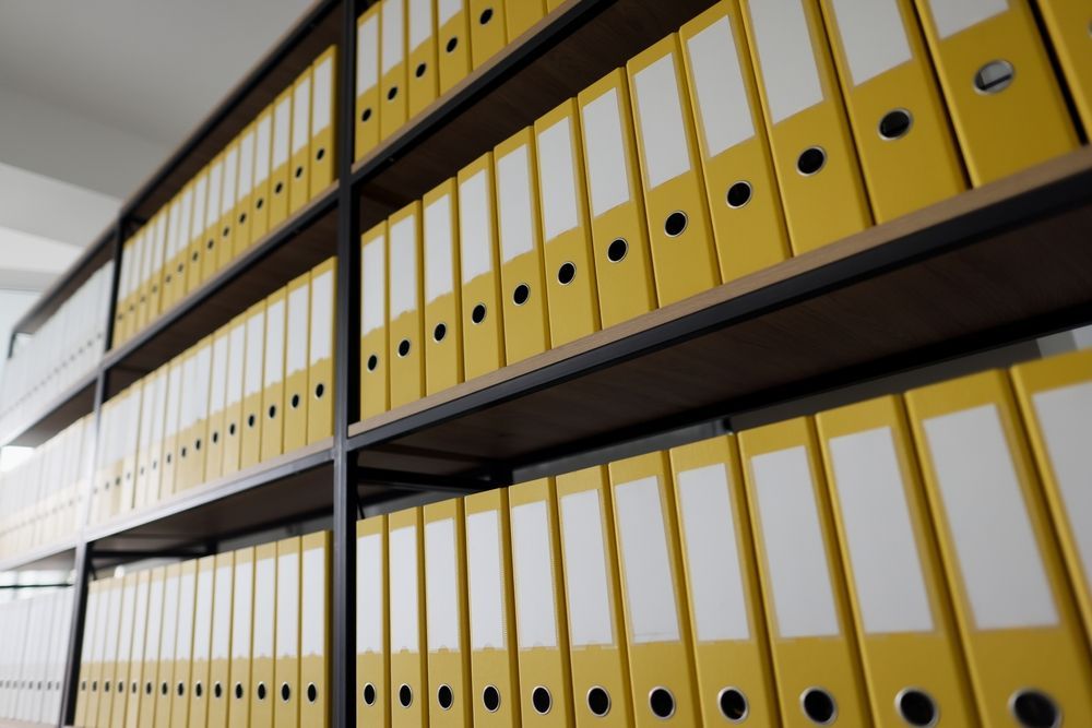 A row of shelves filled with yellow binders with white labels