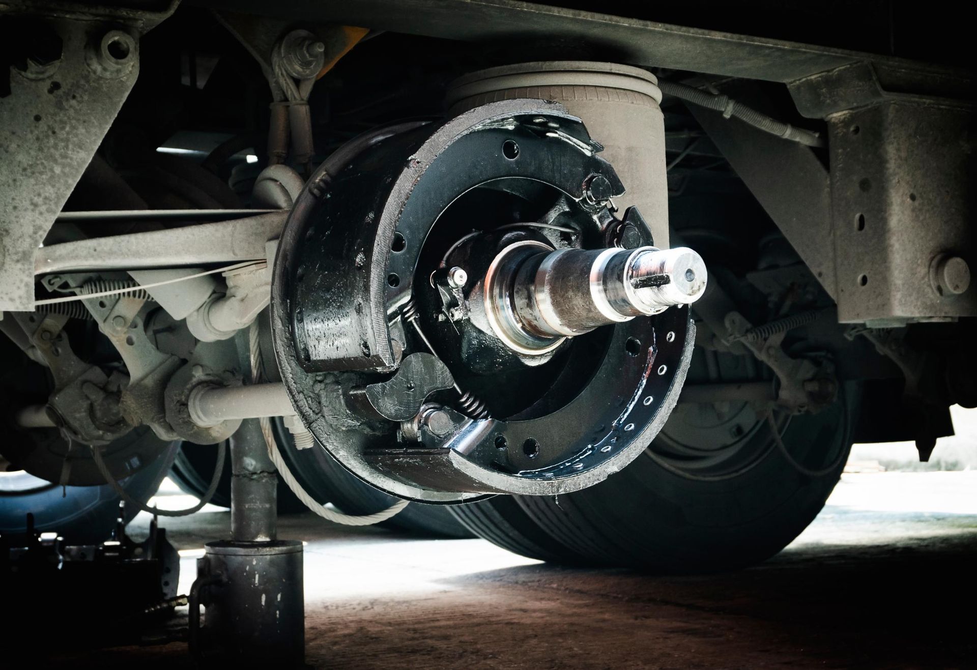 Car’s exposed rear wheel hub and brake assembly under the vehicle during repair