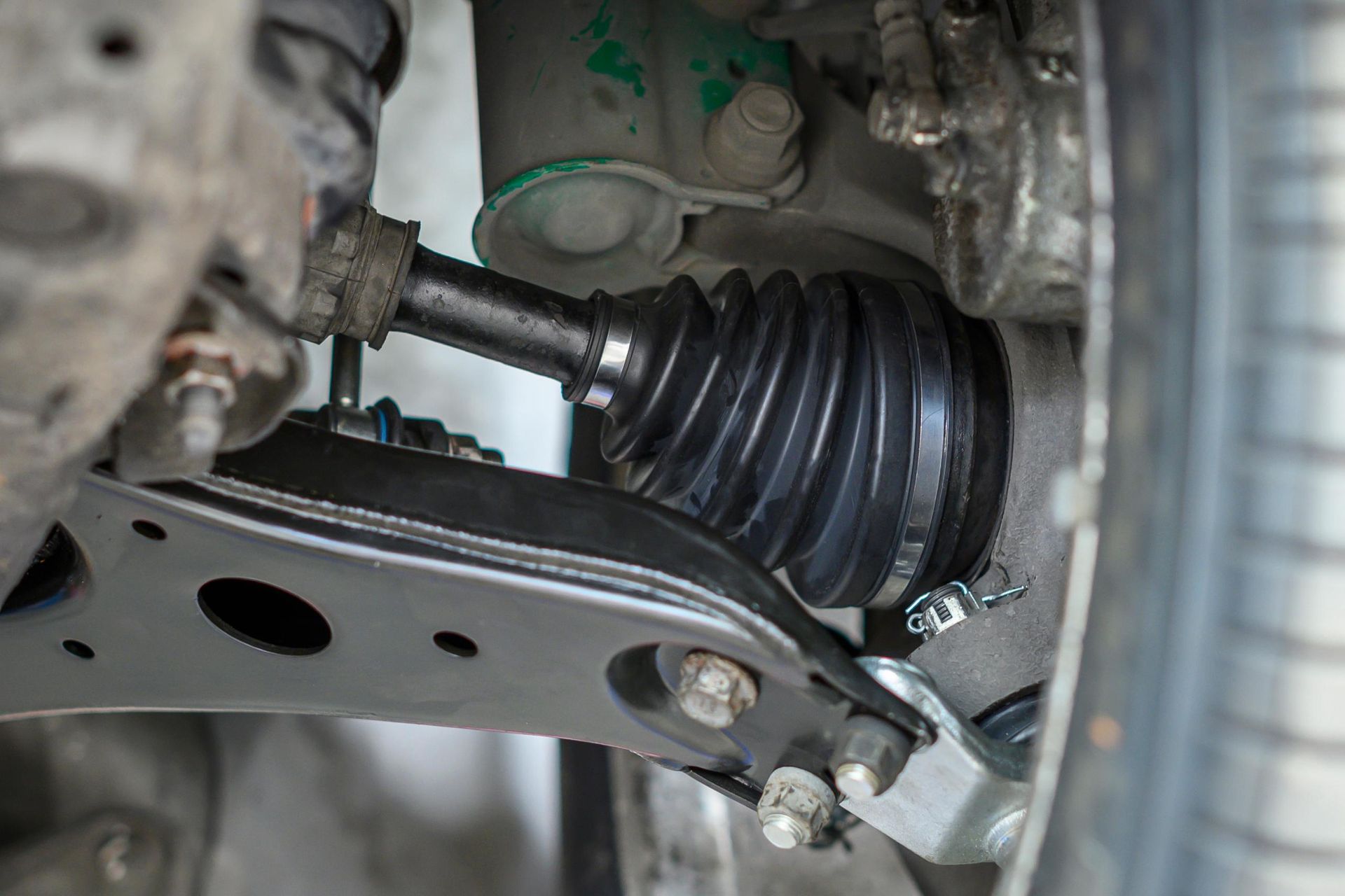 Close-up of a car's CV axle and suspension components with a black rubber boot.