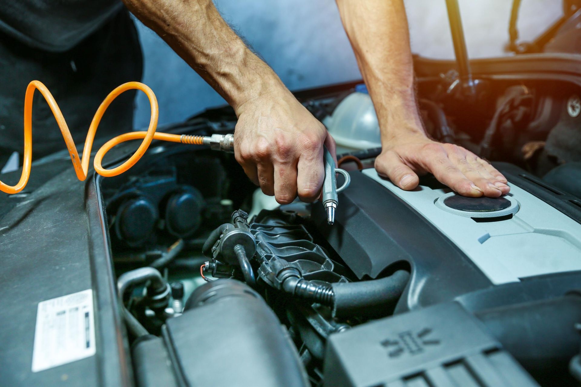 Hands using a ratchet to work on a car engine in a garage