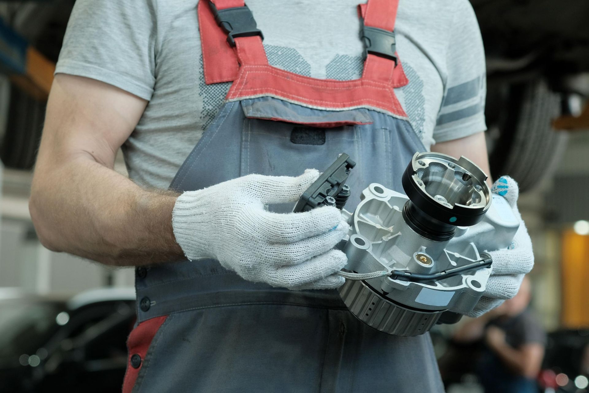 Mechanic in gloves holding a car headlight assembly in a workshop