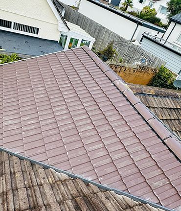 A roof with a lot of tiles on it and a house in the background.