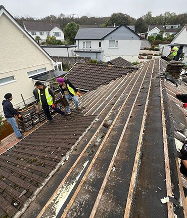 A group of people are working on the roof of a house.