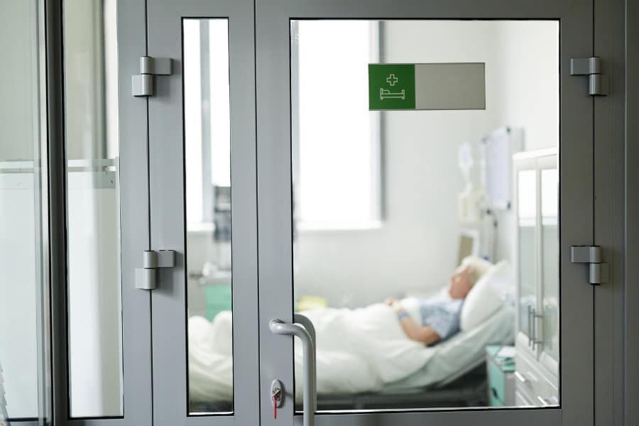 Man is Laying in a Hospital Bed Behind a Glass Door — KeyBay in Canyonleigh, NSW
