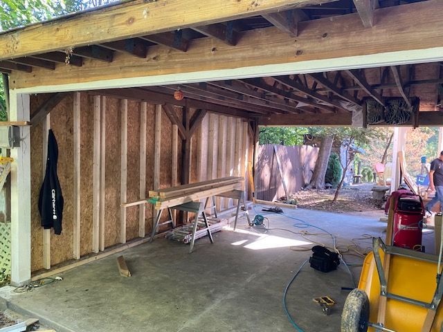 A garage under construction with a wheelbarrow in the middle of it.