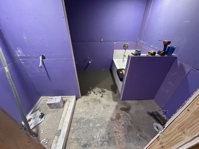 A bathroom under construction with purple walls and a sink.