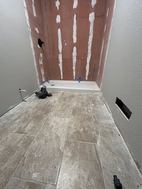 A bathroom under construction with tile floors and a shower stall.