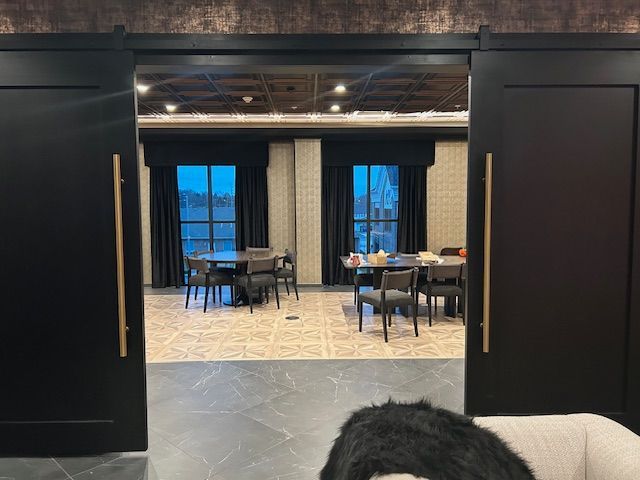 A dog is sitting on a couch in a room with tables and chairs.