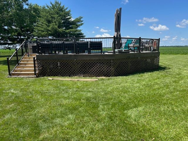 A large deck is sitting in the middle of a lush green field.