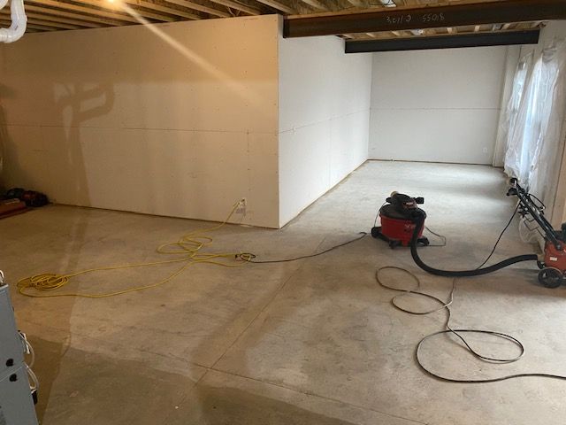 A vacuum cleaner is sitting on the floor of a basement.