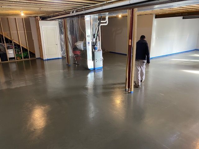 A man is walking through a basement with a concrete floor.