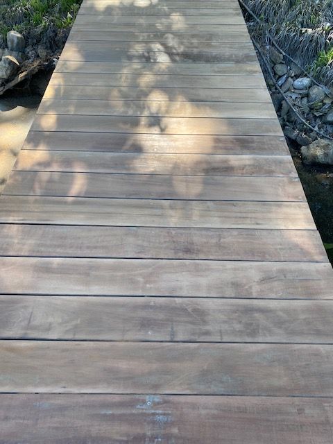 A wooden bridge over a river with a reflection of trees in the water.