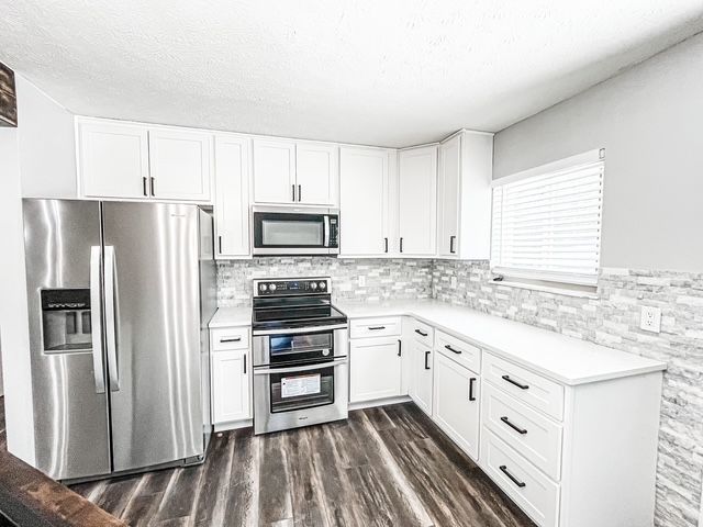 A kitchen with stainless steel appliances and white cabinets.