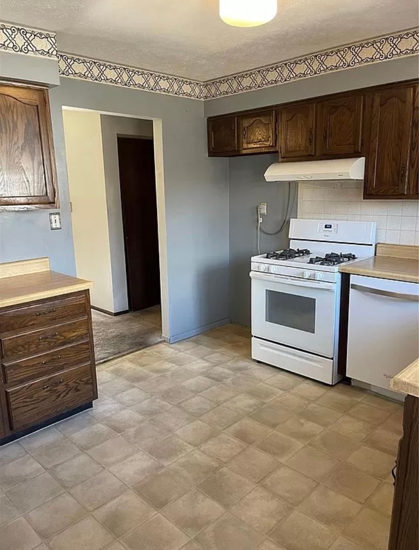 A kitchen with a stove , dishwasher , and cabinets.