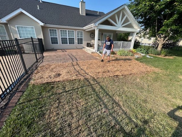 A man is standing in front of a house with a fence.