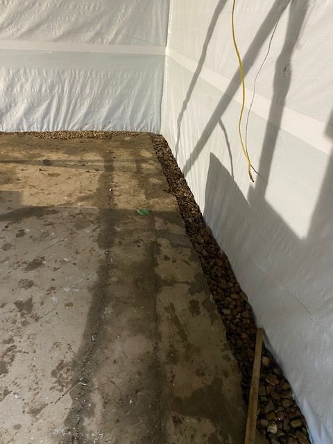 A corner of a room with a concrete floor and a white wall.
