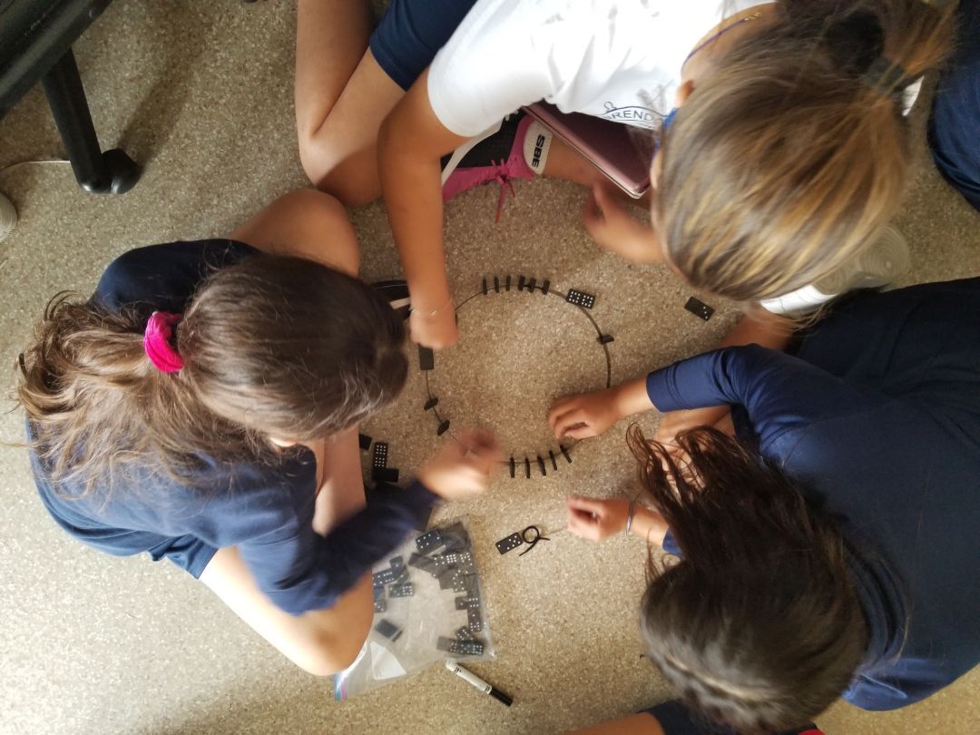 A group of young girls are sitting in a circle on the floor
