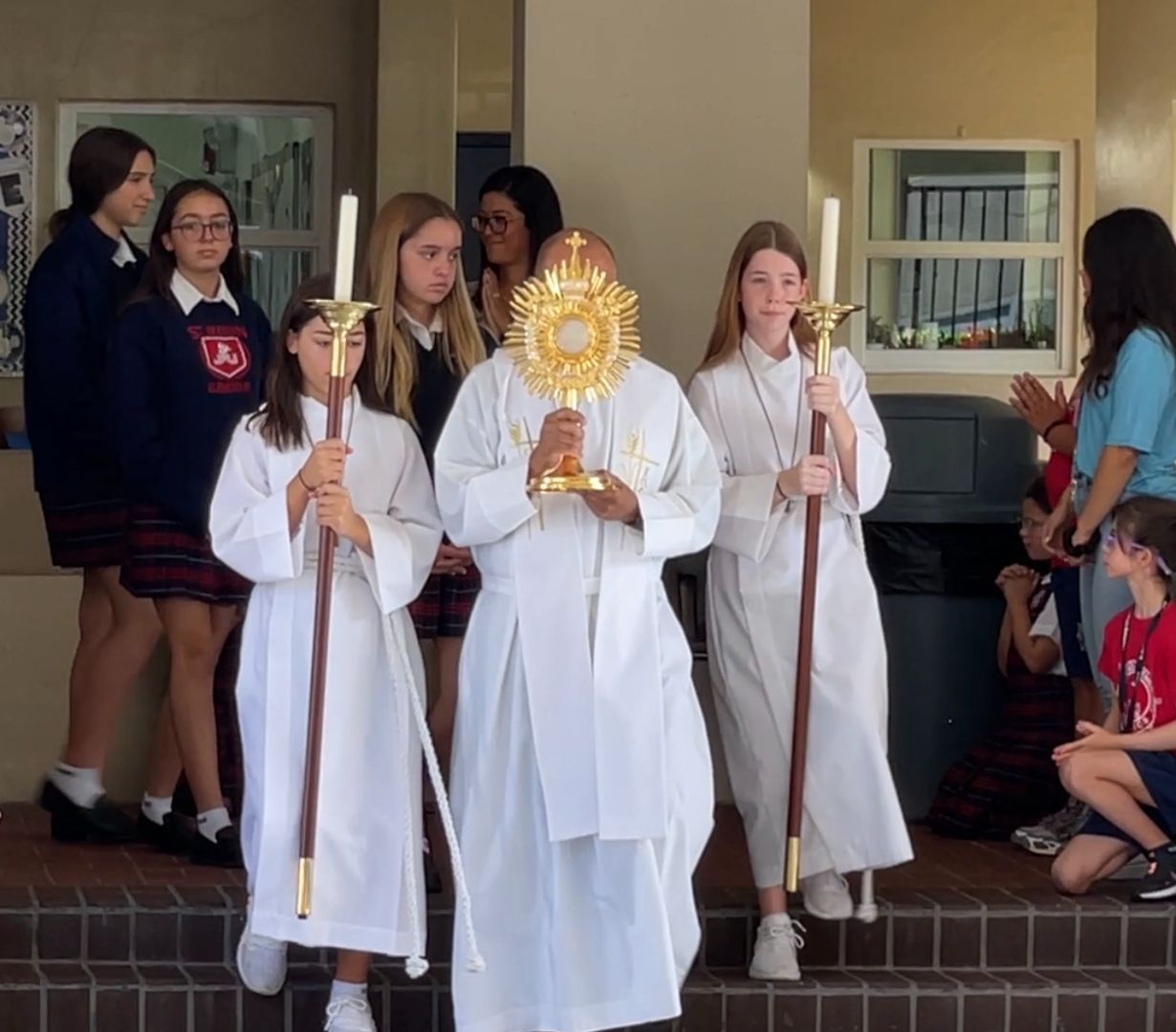 A group of people in white robes are holding candles