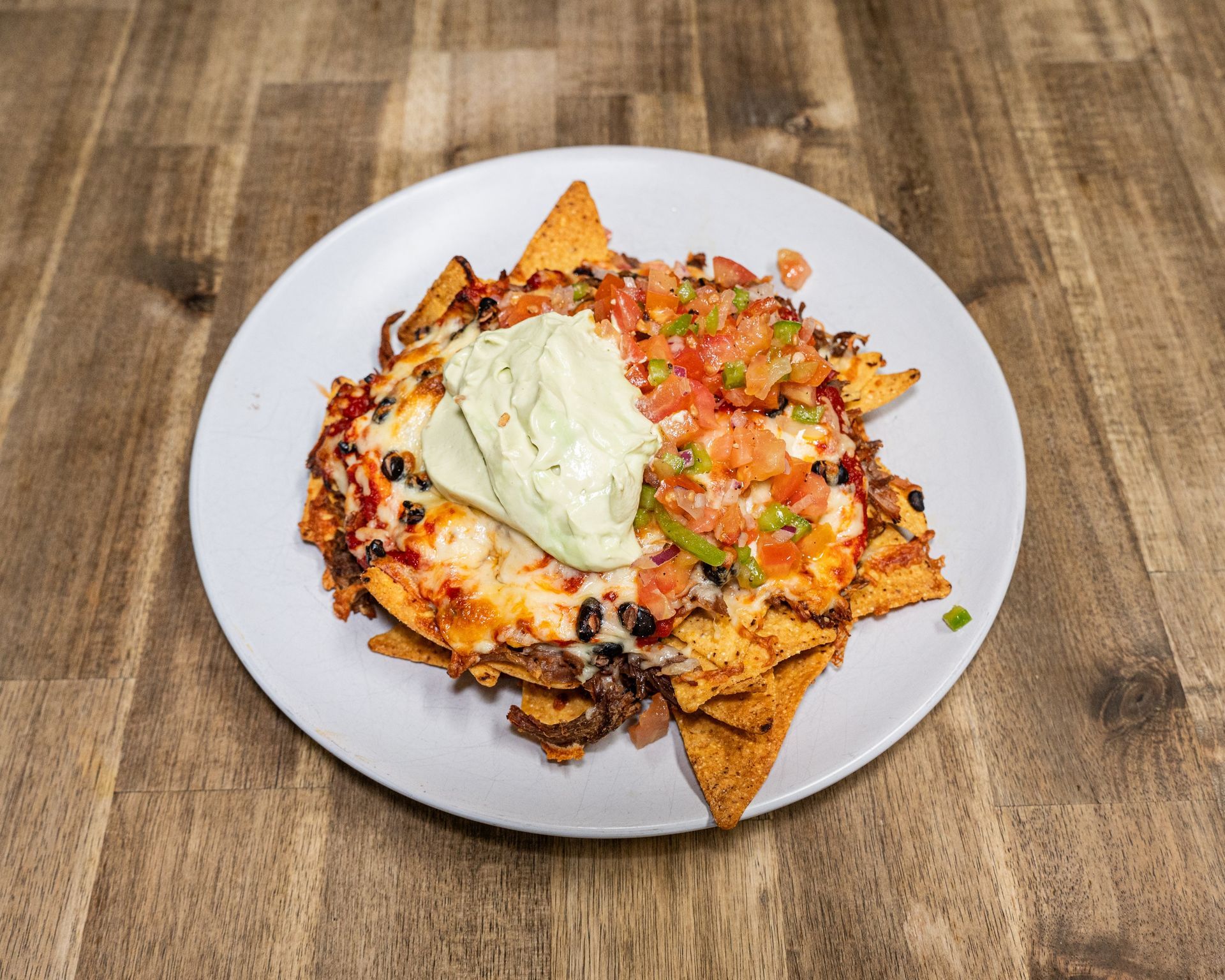Chicken Alfredo Pasta on a White Plate With Fork and Knife on a Wooden Table — Bluewater Diner in Bluewater, QLD