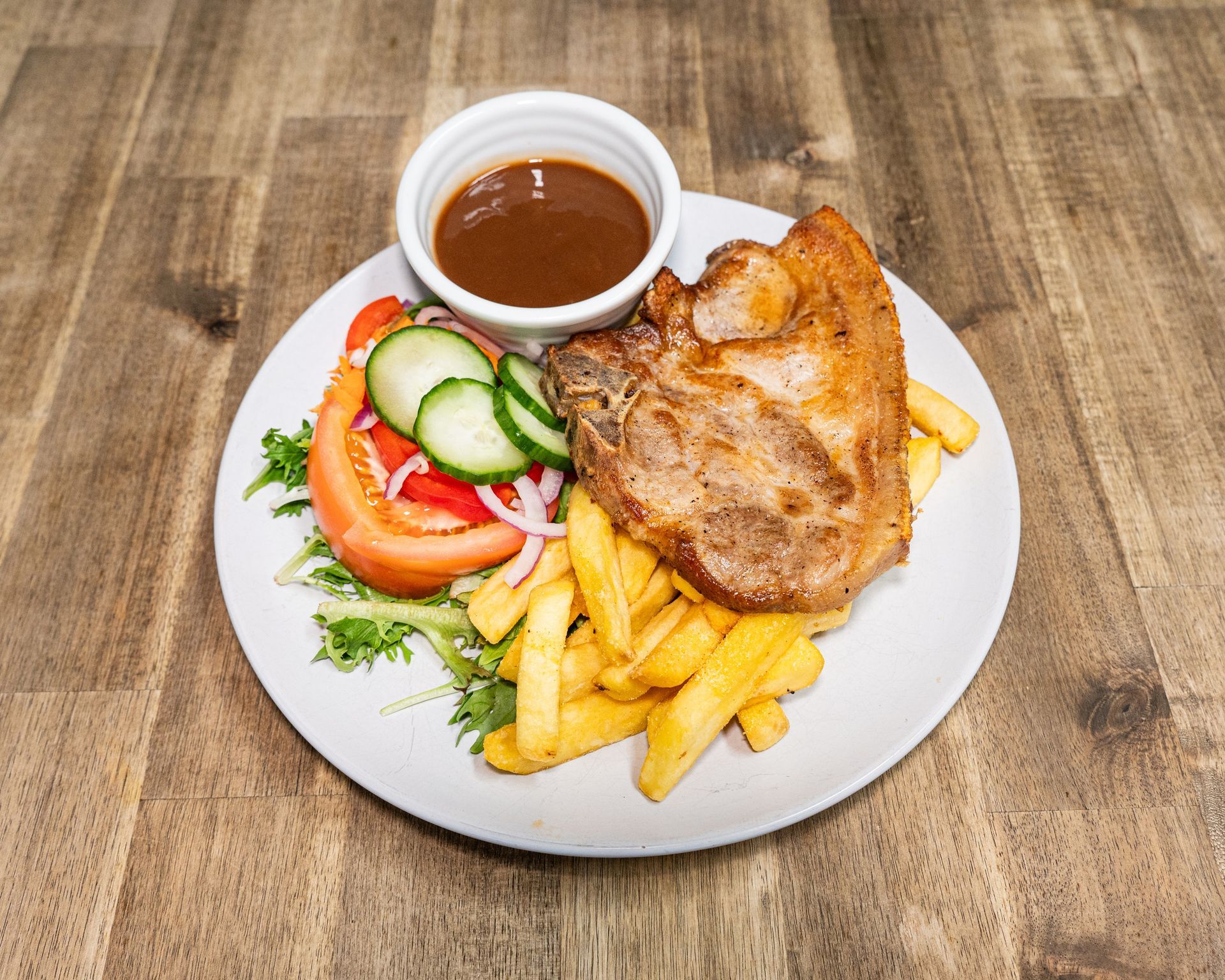 Plate with pork chop, fries, salad, and gravy.