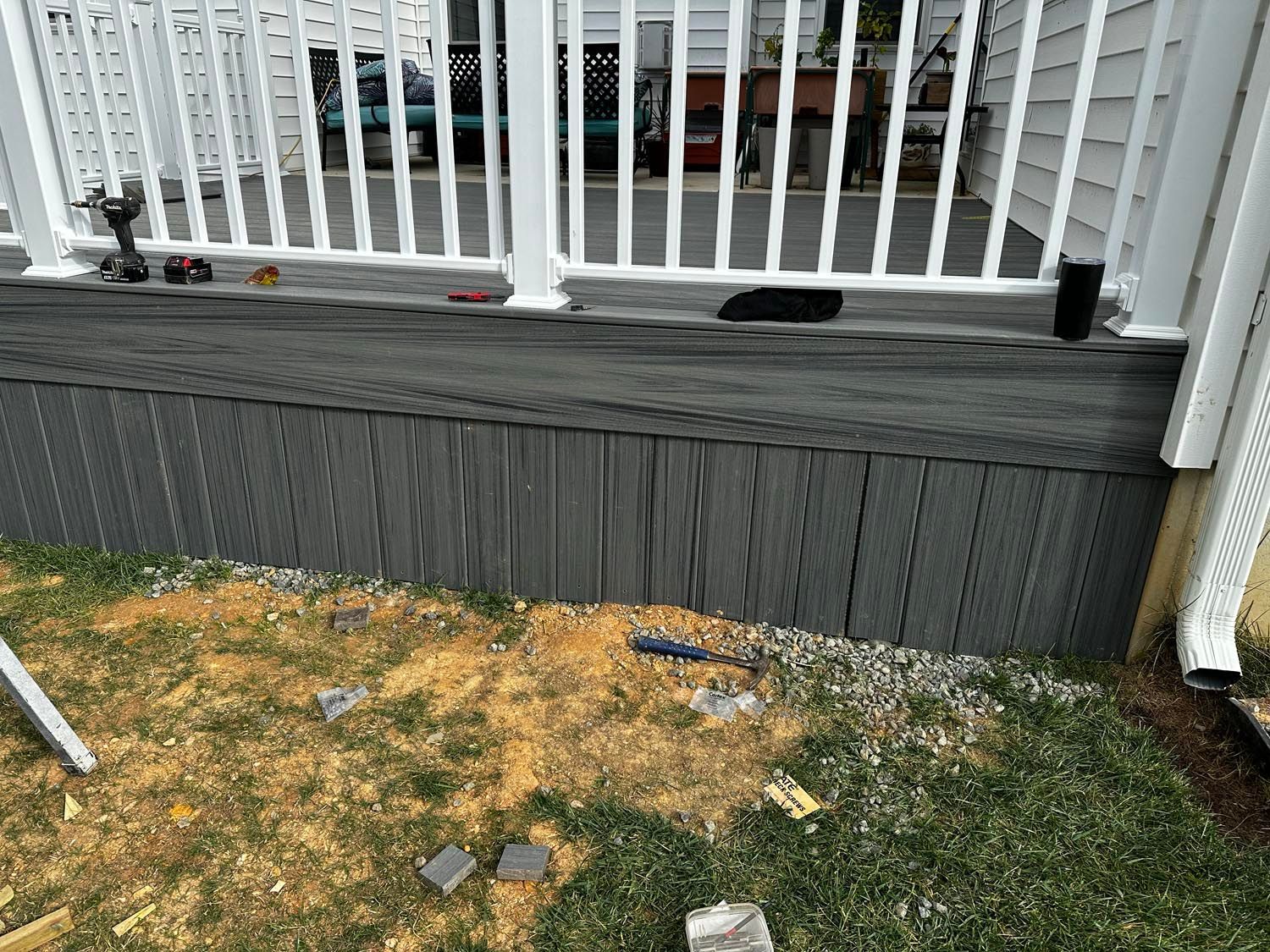 A deck with a white railing is being built next to a house.