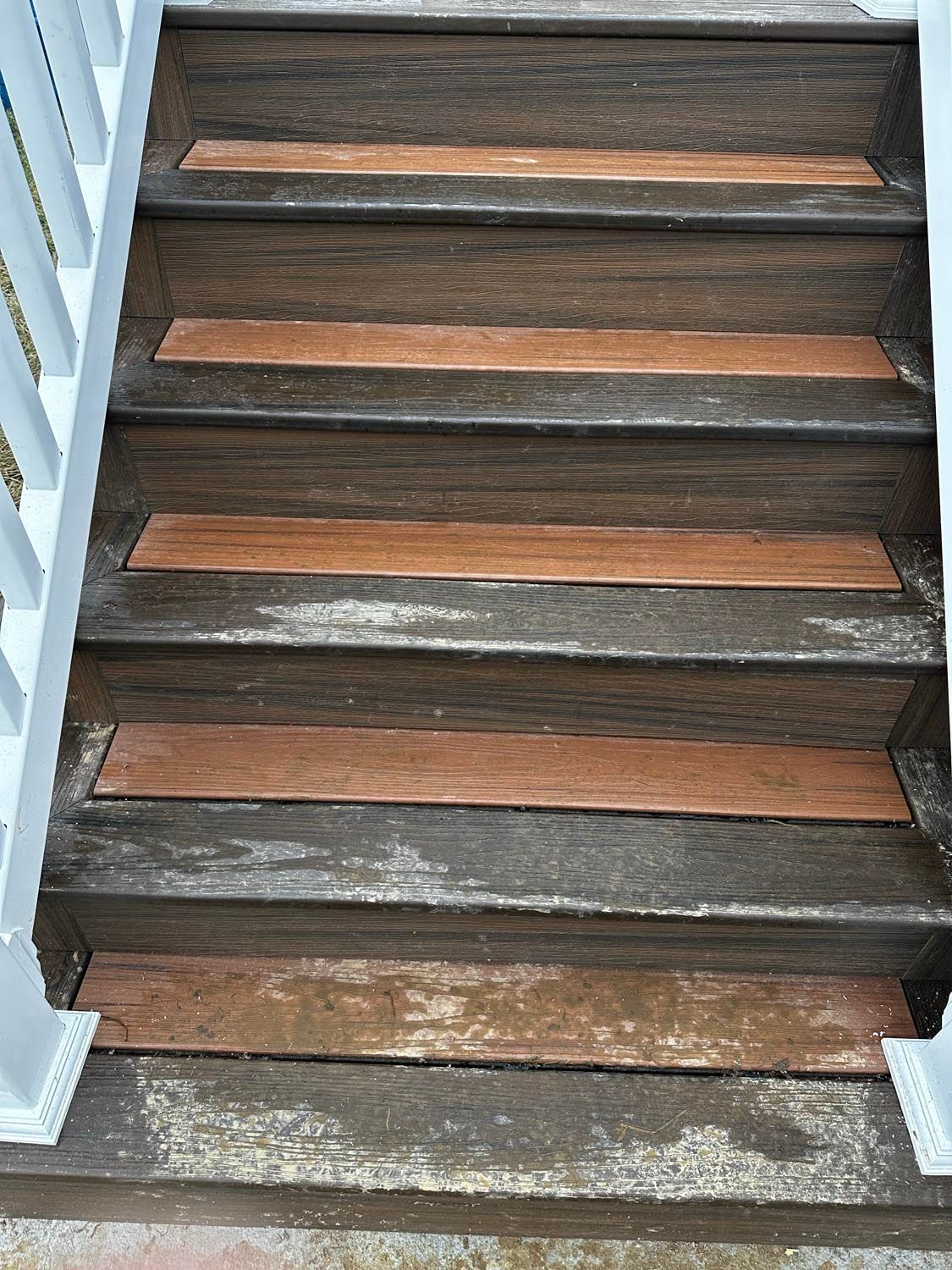 A close up of a set of wooden stairs with a white railing.