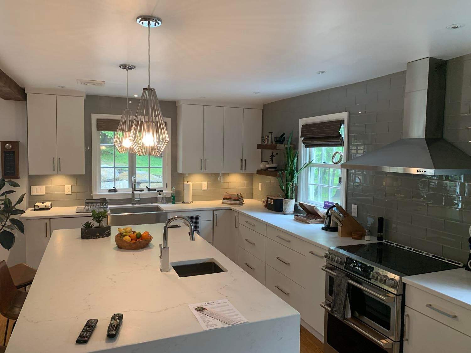 A kitchen with white cabinets , a large island , a sink , a stove , and a window.
