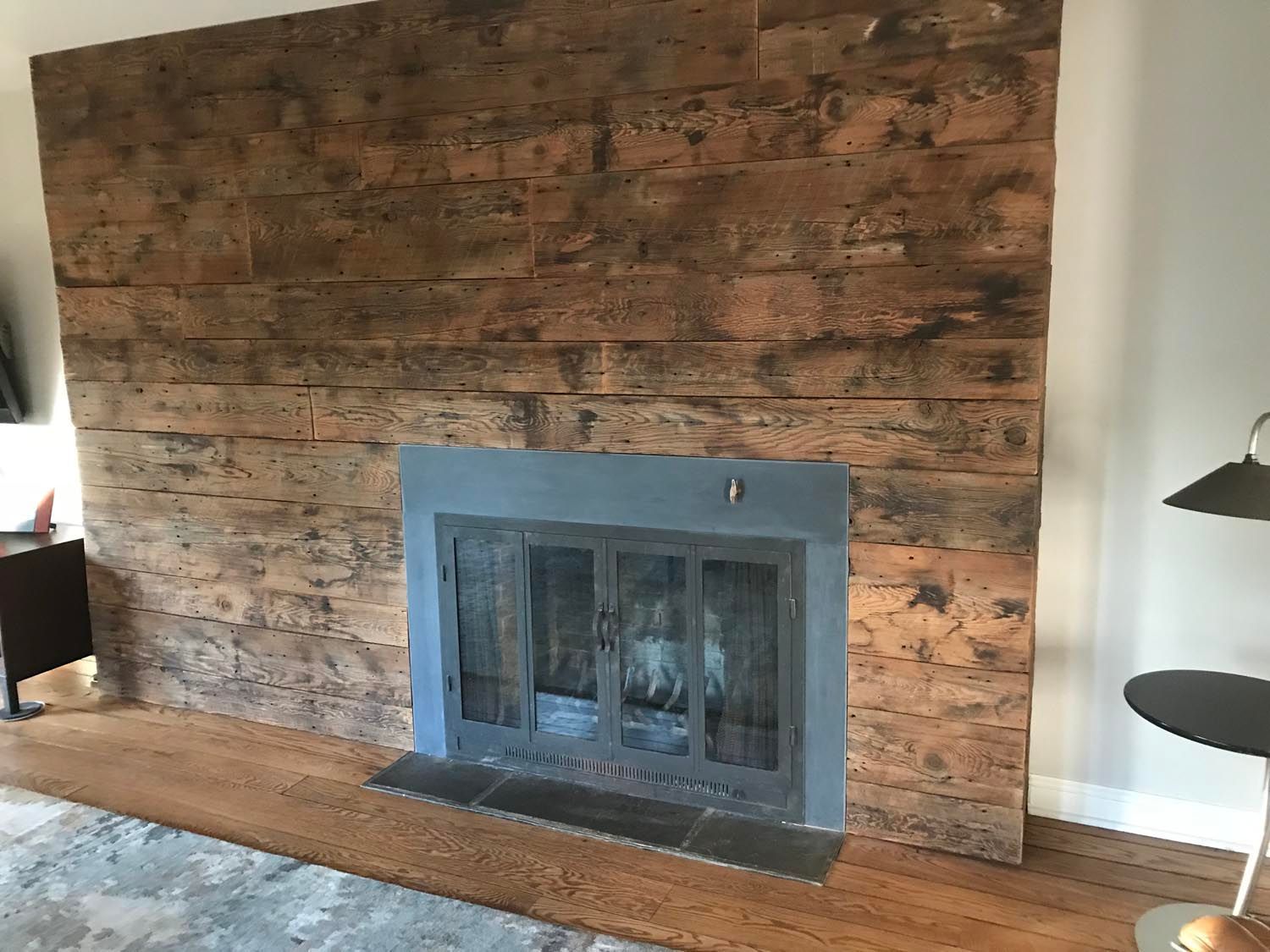A fireplace in a living room with a wooden wall