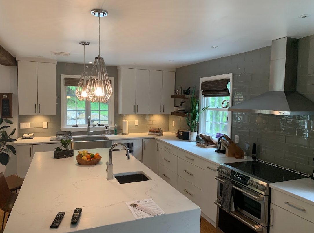 A kitchen with white cabinets , stainless steel appliances and a large island.