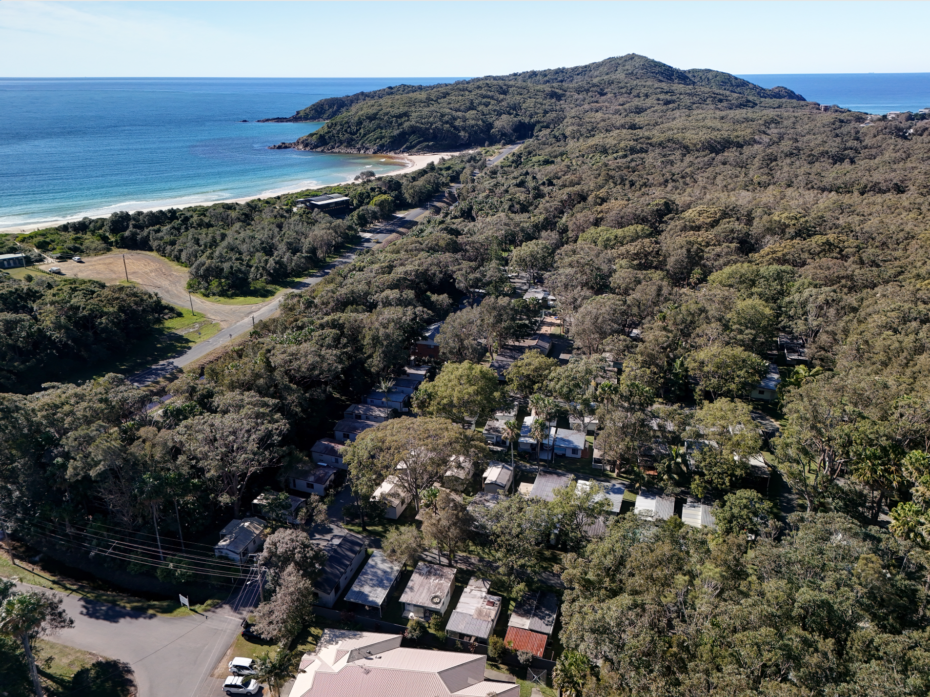 An aerial view of a lighthouse on top of a hill near the ocean — Pacific Palms Caravan Park in Elizabeth Beach, NSW