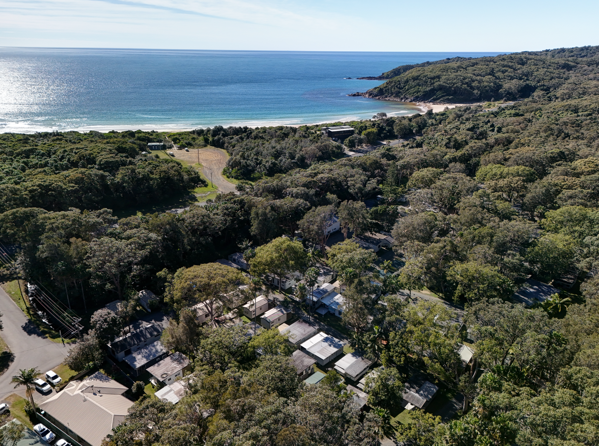 A man is sitting on a beach holding a fishing rod — Pacific Palms Caravan Park in Elizabeth Beach, NSW