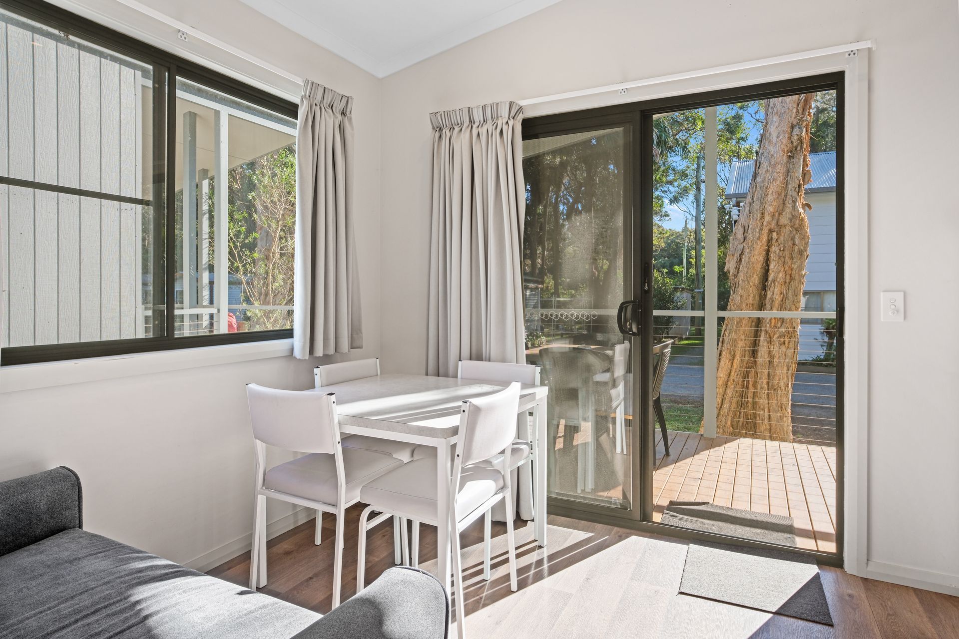 Dining Area With White Table and Chairs, Next to Sliding Door Leading to Outdoor Deck — Pacific Palms Caravan Park in Elizabeth Beach, NSW
