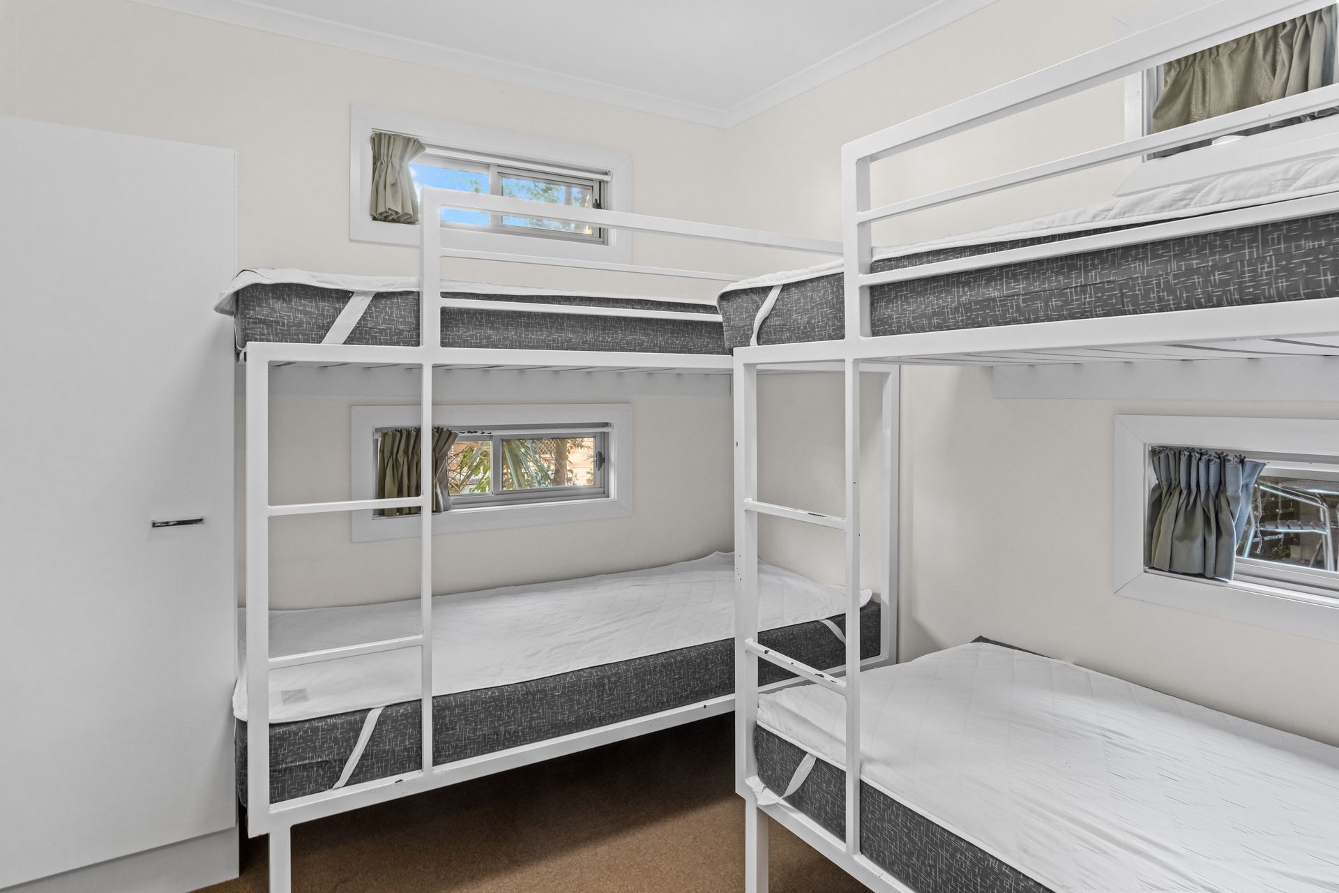 Bedroom with two bunk beds and two small windows.— Pacific Palms Caravan Park in Elizabeth Beach, NSW